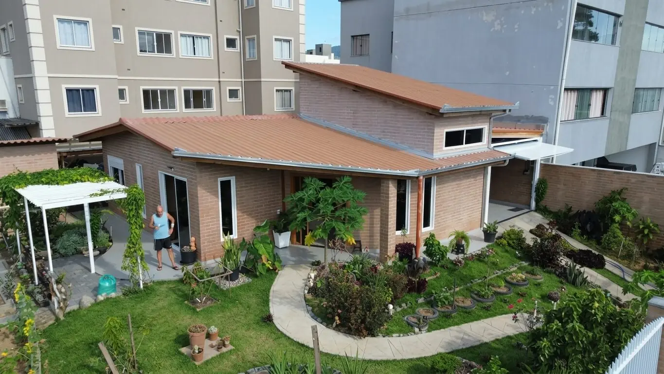 Vista de residência com jardim, varanda e paredes de tijolos aparentes